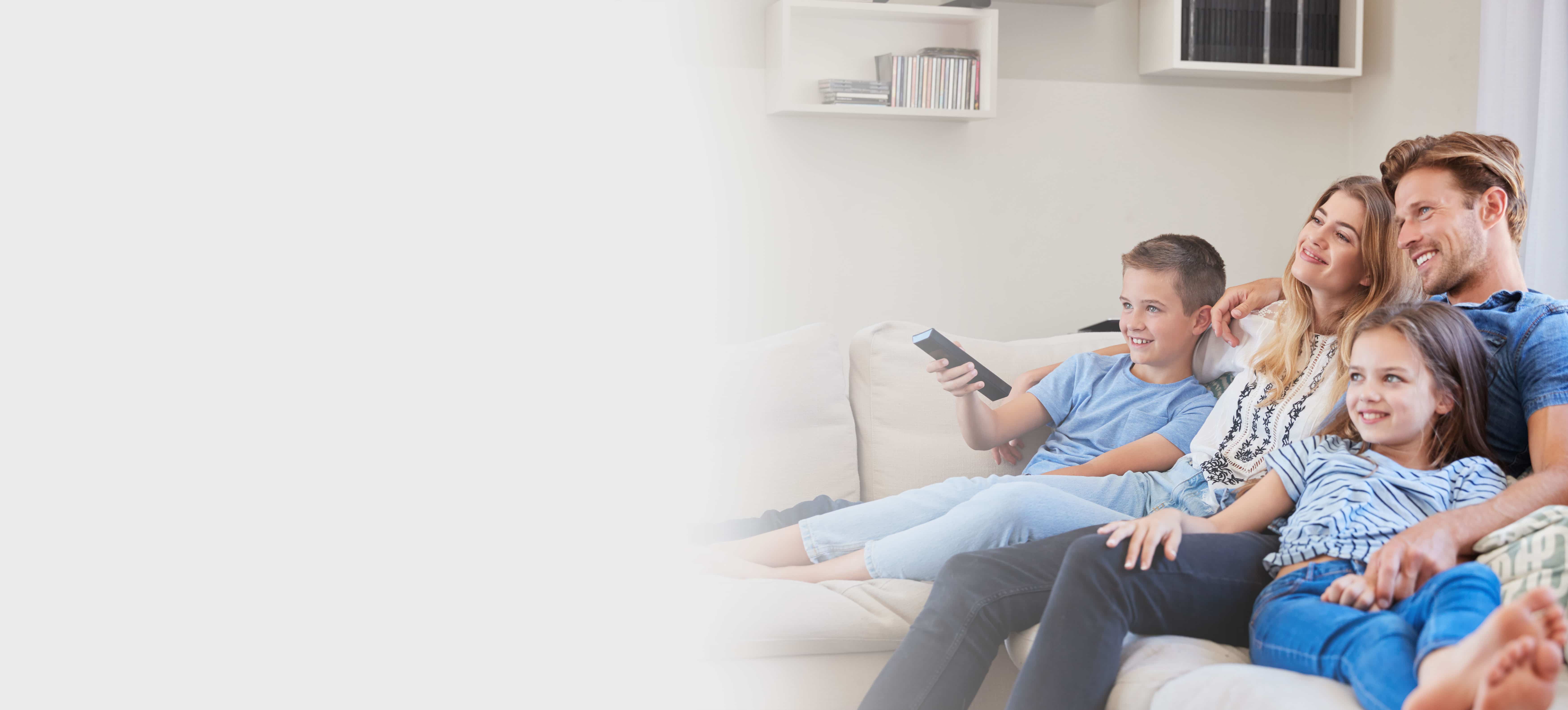 FamilySittingOnSofaAtHomeWatchingTVTogether